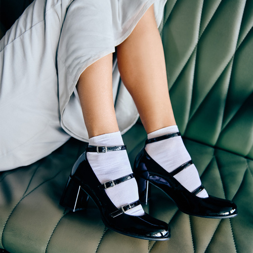 Heeled Mary Janes in black patent leather. 